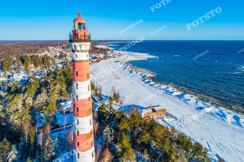 Фотография с дрона, сделанная в Ленинградская область, Россия. На фото запечатлён Осиновецкий маяк, расположенный на берегу Ладожское озеро. Этот фотоснимок показывает старинный маяк на фоне прибрежного ландшафта Ладоги, воды озера и суровой северной природы. Изображение передаёт атмосферу уединения, исторического наследия и красоты природных пейзажей. Фото подчёркивает туристическую привлекательность региона и тему путешествий по России. Иллюстрация может использоваться как картинка или слайд, посвящённые маякам, природе и маршрутам для путешествий.